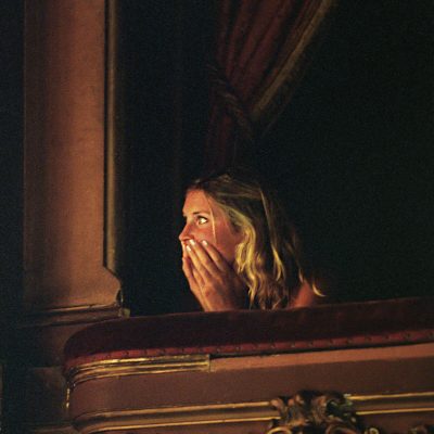 mujer sentada en un palco de teatro, mirando una función con total concentración