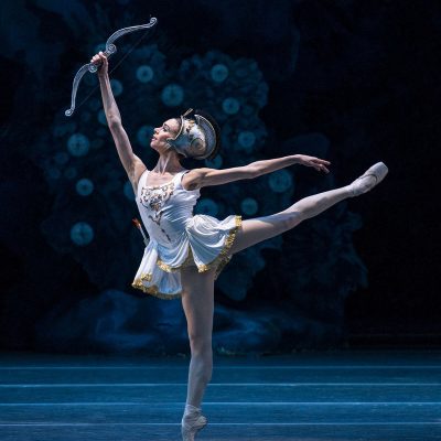 bailarina con casco, sostiene un arco en su mano y está en pose arabesque